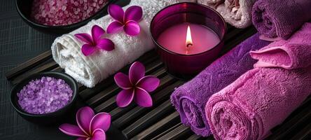 Decorative spa setting with purple towels and candles. Luxurious spa ambiance with floral elements. Concept of indulgence, tranquility, relaxation space, and elegant design. photo