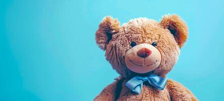 Plush toy bear with blue bow on a light blue background. Cute stuffed animal. Concept of childhood, toys, softness, innocence. Copy space photo