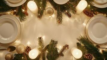 Festive holiday dinner table with white plates and lit candles. Christmas table setting with evergreen branches and ornaments. Concept of festive decor, celebration, winter holiday, cozy ambiance photo