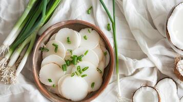 Sliced coconut milk jelly garnished with green onions, presented in a rustic dish. A refreshing Thai dessert. Concept of vegan desserts, coconut recipes, and light treats. photo
