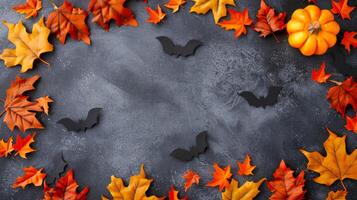 Autumn leaves with black bats and pumpkins on dark background. Halloween decoration. Concept of fall season, festive decor, celebration, spooky design. Banner. Copy space photo