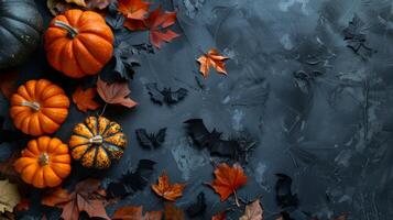 Autumn pumpkins with black bats and leaves on dark textured background. Halloween-themed banner with copy space. Concept of autumn decor, Halloween celebration, seasonal decoration photo
