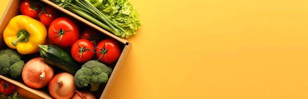 Fresh vegetables in a wooden crate on a yellow background. Healthy eating, organic produce, nutrition, farm-to-table. Concept of healthy lifestyle, diet, colorful food. Banner. Copy space photo