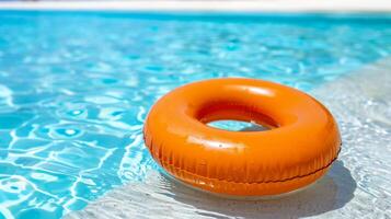 Bright Orange Inflatable Ring Floating in Clear Blue Swimming Pool Water on a Sunny Day photo