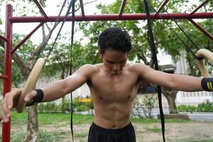 Asian man practicing gymnastics, doing gymnastics bar and hoop exercises and stretching, resting for sports. photo