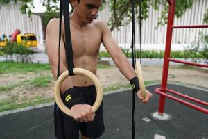 Asian man practicing gymnastics, doing gymnastics bar and hoop exercises and stretching, resting for sports. photo