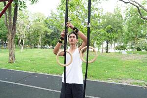 Asian man practicing gymnastics doing gymnastics bar and hoop exercises and stretching and resting for sports. photo