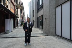 ASian man is dancing in hip hop style at outdoor space. Professional solo dancer is performing in public area. photo