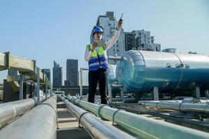 Urban rooftop scene showing a young engineer with a radio, inspecting and adjusting equipment in a sunny city environment. Safety and precision at work. photo