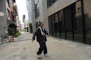 ASian man is dancing in hip hop style at outdoor space. Professional solo dancer is performing in public area. photo