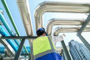 Industrial engineer adjusting pipeline valve with radio communication on construction site. Engineer on urban construction site using radio to coordinate with team on a sunny industrial rooftop. photo