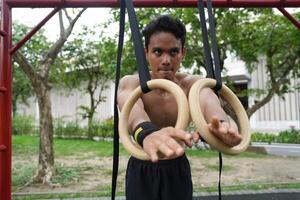 Asian man practicing gymnastics, doing gymnastics bar and hoop exercises and stretching, resting for sports. photo