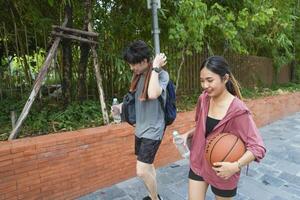 The male and female basketball players practice using the ball in the park court diligently and happily. photo