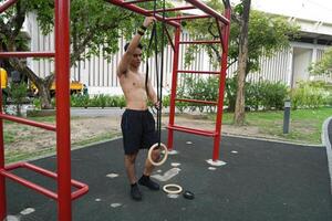Asian man practicing gymnastics, doing gymnastics bar and hoop exercises and stretching, resting for sports. photo