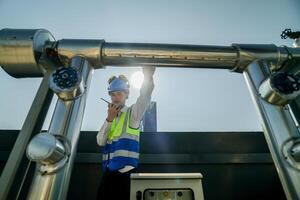Urban rooftop scene showing a young engineer with a radio, inspecting and adjusting equipment in a sunny city environment. Safety and precision at work. photo