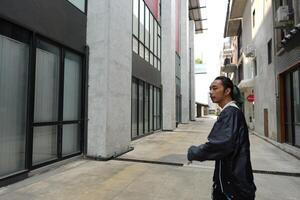 ASian man is dancing in hip hop style at outdoor space. Professional solo dancer is performing in public area. photo