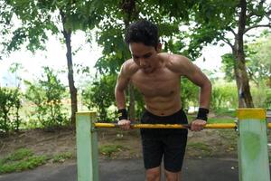 Asian man practicing gymnastics, doing gymnastics bar and hoop exercises and stretching, resting for sports. photo