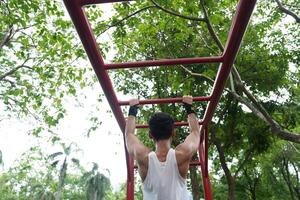 Asian man practicing gymnastics, doing gymnastics bar and hoop exercises and stretching, resting for sports. photo