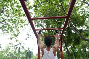 Asian man practicing gymnastics, doing gymnastics bar and hoop exercises and stretching, resting for sports. photo