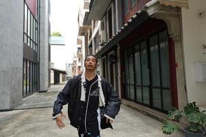 ASian man is dancing in hip hop style at outdoor space. Professional solo dancer is performing in public area. photo