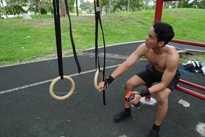Asian man practicing gymnastics, doing gymnastics bar and hoop exercises and stretching, resting for sports. photo