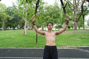 Asian man practicing gymnastics, doing gymnastics bar and hoop exercises and stretching, resting for sports. photo