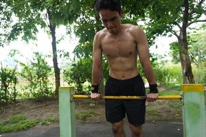 Asian man practicing gymnastics, doing gymnastics bar and hoop exercises and stretching, resting for sports. photo