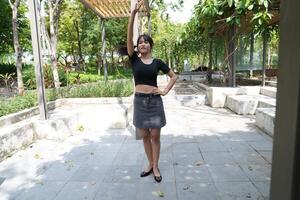 Asian woman dancing in the middle of a park photo