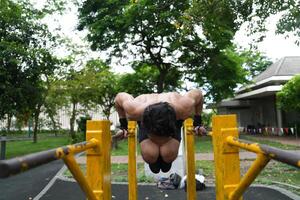 Asian man practicing gymnastics, doing gymnastics bar and hoop exercises and stretching, resting for sports. photo