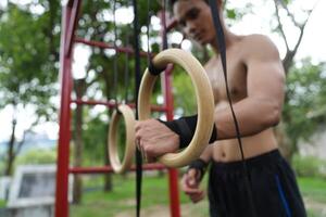 Asian man practicing gymnastics, doing gymnastics bar and hoop exercises and stretching, resting for sports. photo