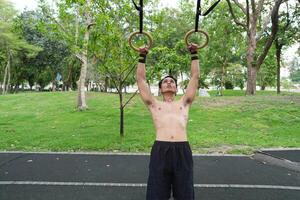 Asian man practicing gymnastics, doing gymnastics bar and hoop exercises and stretching, resting for sports. photo