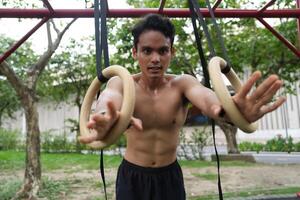 Asian man practicing gymnastics, doing gymnastics bar and hoop exercises and stretching, resting for sports. photo