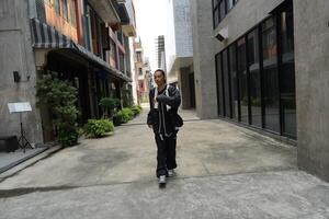 ASian man is dancing in hip hop style at outdoor space. Professional solo dancer is performing in public area. photo