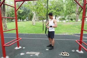 Asian man practicing gymnastics doing gymnastics bar and hoop exercises and stretching and resting for sports. photo