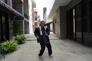 ASian man is dancing in hip hop style at outdoor space. Professional solo dancer is performing in public area. photo