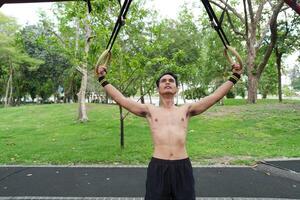 Asian man practicing gymnastics, doing gymnastics bar and hoop exercises and stretching, resting for sports. photo