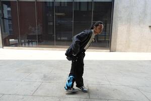 ASian man is dancing in hip hop style at outdoor space. Professional solo dancer is performing in public area. photo