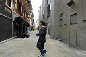 ASian man is dancing in hip hop style at outdoor space. Professional solo dancer is performing in public area. photo