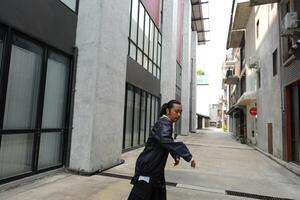 ASian man is dancing in hip hop style at outdoor space. Professional solo dancer is performing in public area. photo