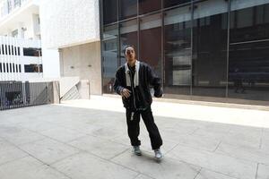 ASian man is dancing in hip hop style at outdoor space. Professional solo dancer is performing in public area. photo