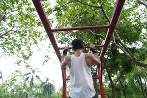 Asian man practicing gymnastics, doing gymnastics bar and hoop exercises and stretching, resting for sports. photo