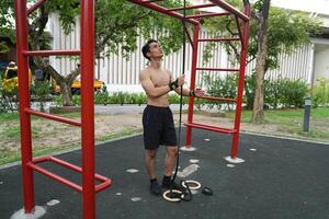 Asian man practicing gymnastics, doing gymnastics bar and hoop exercises and stretching, resting for sports. photo