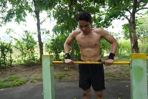 Asian man practicing gymnastics, doing gymnastics bar and hoop exercises and stretching, resting for sports. photo