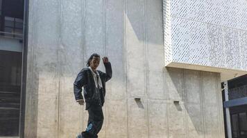 ASian man is dancing in hip hop style at outdoor space. Professional solo dancer is performing in public area. photo