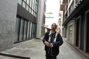 ASian man is dancing in hip hop style at outdoor space. Professional solo dancer is performing in public area. photo