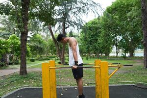 Asian man practicing gymnastics, doing gymnastics bar and hoop exercises and stretching, resting for sports. photo