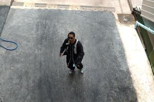 ASian man is dancing in hip hop style at outdoor space. Professional solo dancer is performing in public area. photo