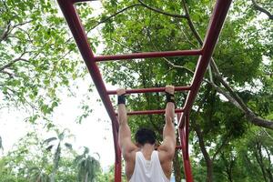 Asian man practicing gymnastics, doing gymnastics bar and hoop exercises and stretching, resting for sports. photo