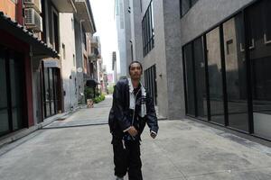 ASian man is dancing in hip hop style at outdoor space. Professional solo dancer is performing in public area. photo