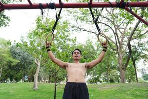 Asian man practicing gymnastics, doing gymnastics bar and hoop exercises and stretching, resting for sports. photo